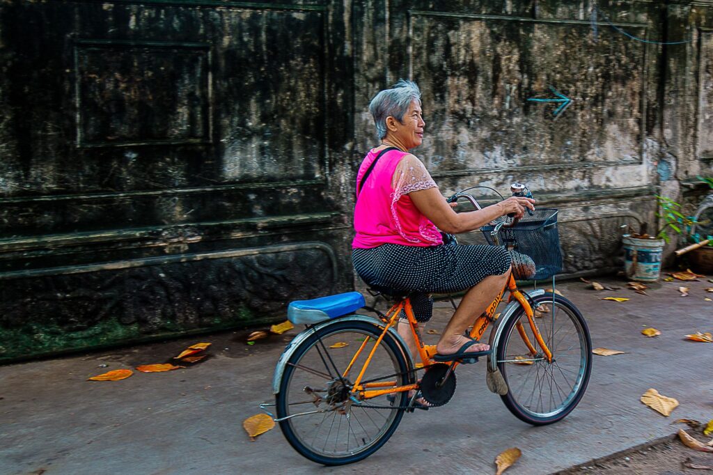 Old but Fit. Age, just a number. An old Thai woman happily paddling away on her bicycle, Bangkok, Thailand.
